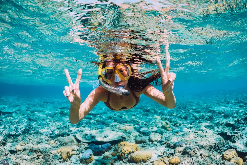 Happy young woman swimming underwater in the tropical ocean.