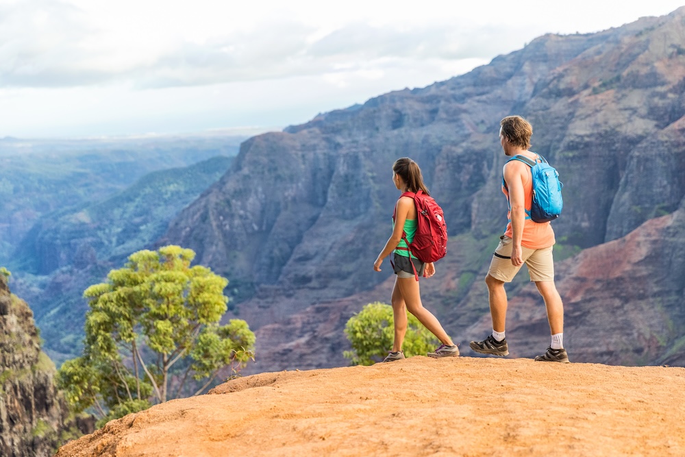 Woman and man walking on hike in Waimea Canyon State Park, Kauai, Hawaii, USA.